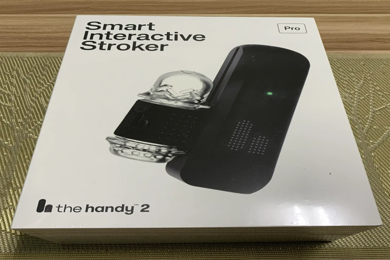Boîte du The Handy 2 Pro Smart Interactive Stroker posée sur une table, avec l’image du produit en façade.