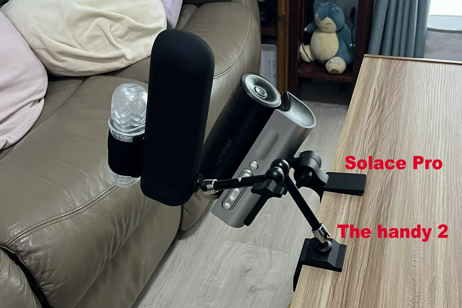 Lovense Solace Pro et The Handy 2 installés côte à côte au bord d'une table avec leurs supports respectifs, montrant les différences de positionnement et de réglage de l'angle